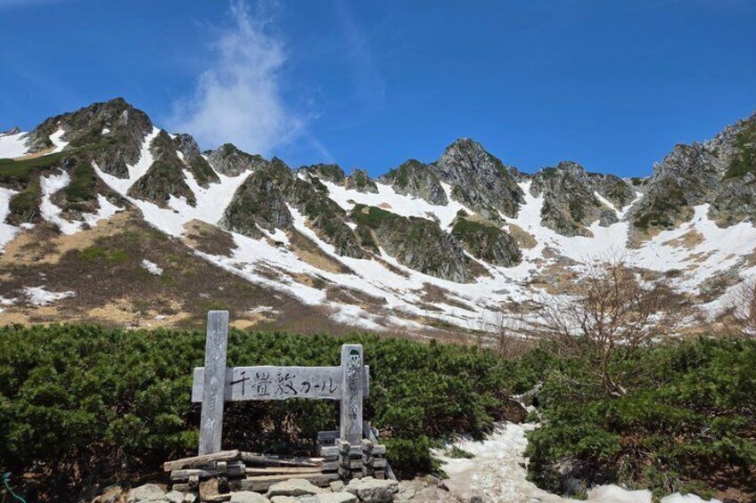 A mountain trail with a signpost and snow-capped peaks in the background. 2