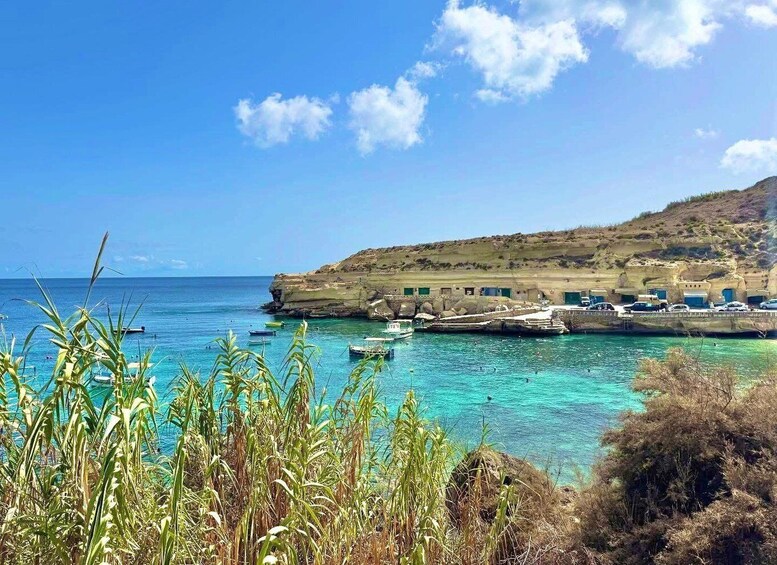 A coastal scene with boats, a rocky cliff, and a clear blue sky. 1