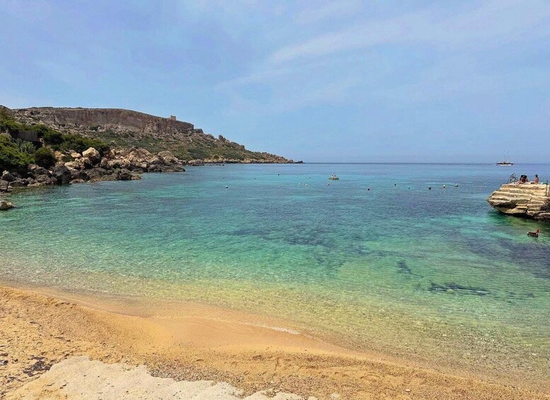 A clear coastal beach with rocky outcrops and calm turquoise waters. 2
