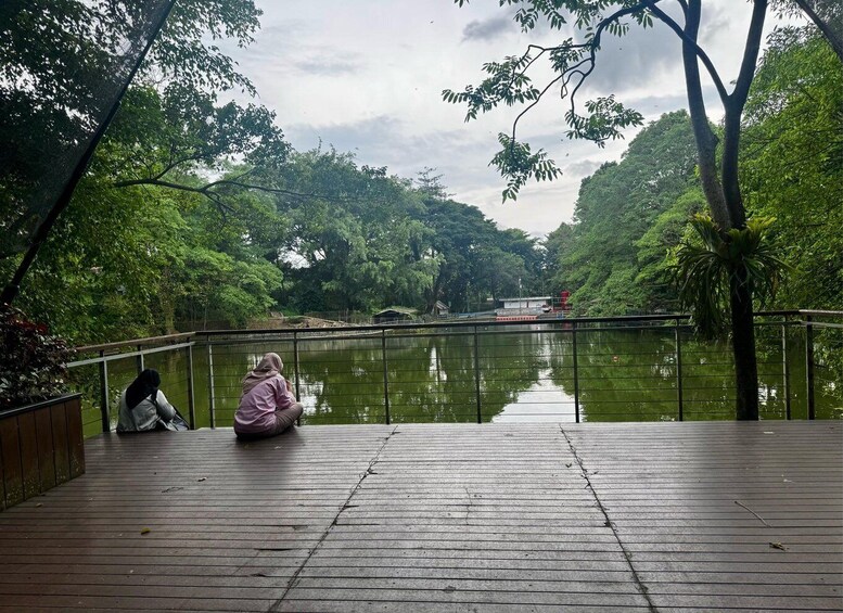 A person sitting on a wooden deck overlooking a calm river, surrounded by lush greenery. 5