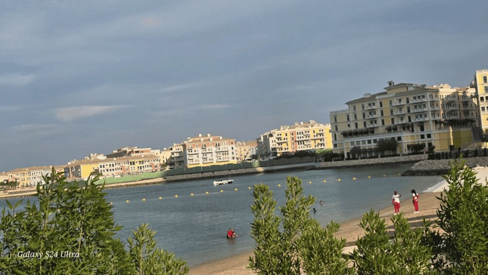 A waterfront with buildings, a boat, and people by the shore. 4