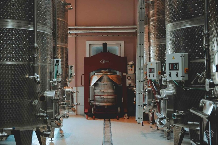 A brewery interior with stainless steel tanks, a brewing kettle, and control panels. 3