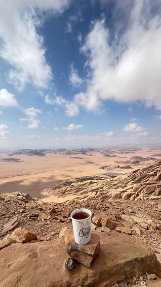 A paper cup labeled 'Smile Day' on a rock with a desert landscape and mountains in the background. 5