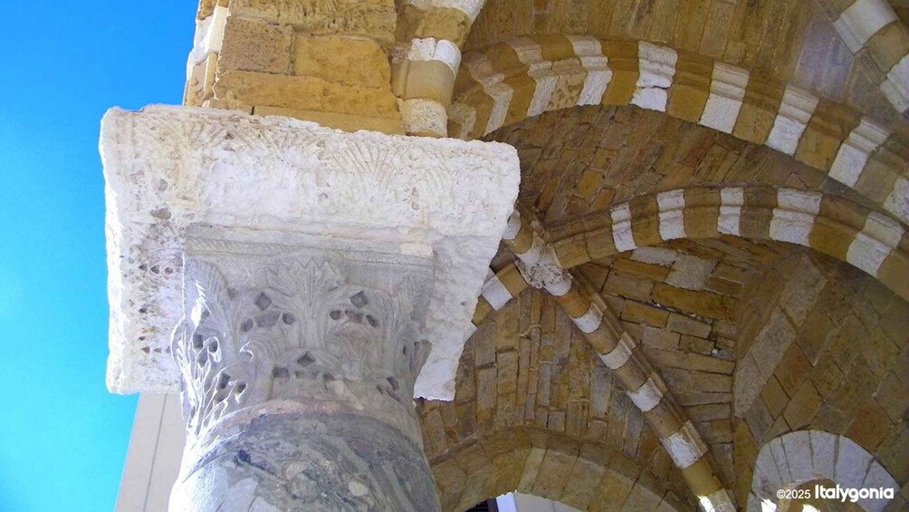 A stone column with intricate carvings, part of a historic building with arches. 3