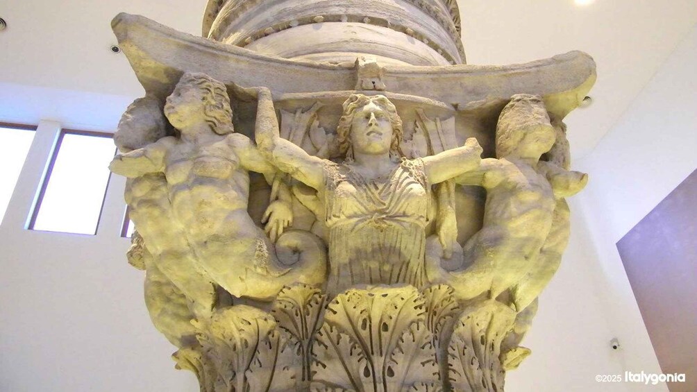 A detailed sculpture with a central figure, flanked by two animal-like figures, set against a plain wall. 4