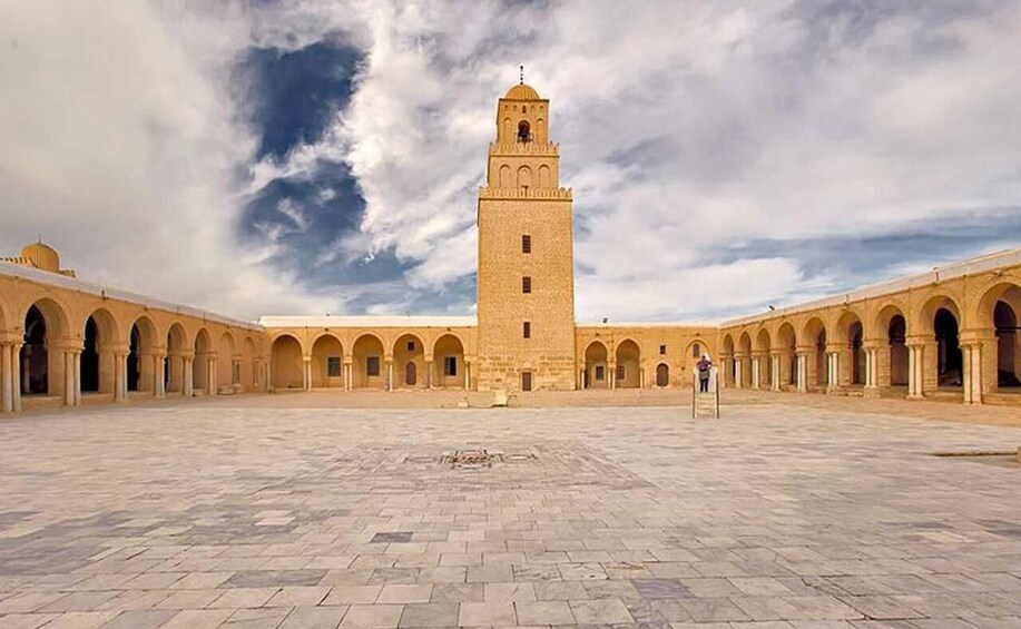 A large open courtyard with a tall tower and arches. 1