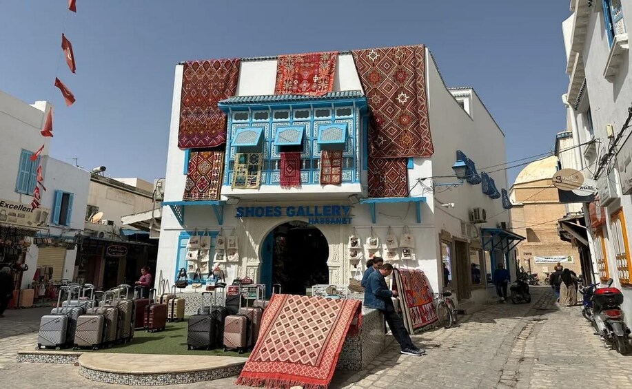 A traditional building with a sign reading 'SHOES GALLERY' and a variety of luggage displayed outside. 3