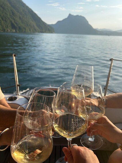 People toasting with wine glasses on a boat with a mountainous landscape in the background. 3