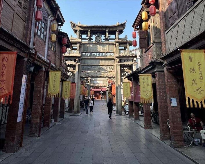 A traditional street with wooden buildings, red lanterns, and yellow banners. 3