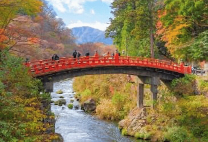 A red bridge over a river with autumn foliage and mountains in the background. 4
