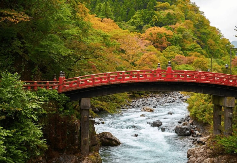 A red bridge over a flowing river surrounded by autumn foliage. 1