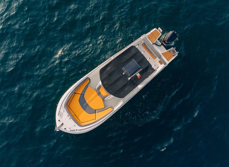 An aerial view of a speedboat with a yellow and gray seating area, a motor at the stern, and a wake behind it. 1