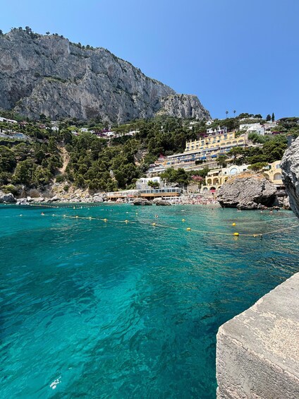 A coastal town with clear turquoise waters, rocky cliffs, and colorful buildings. 3