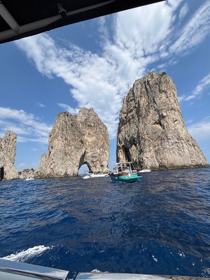 A boat navigating through a narrow waterway flanked by large rock formations with an archway. 3