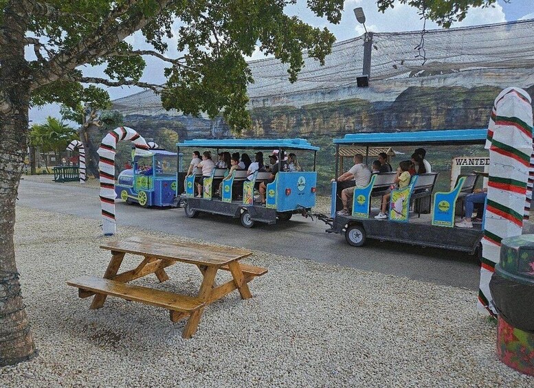 A group of people riding a small, colorful train-like vehicle with a 'WANTED' sign in the background. 5