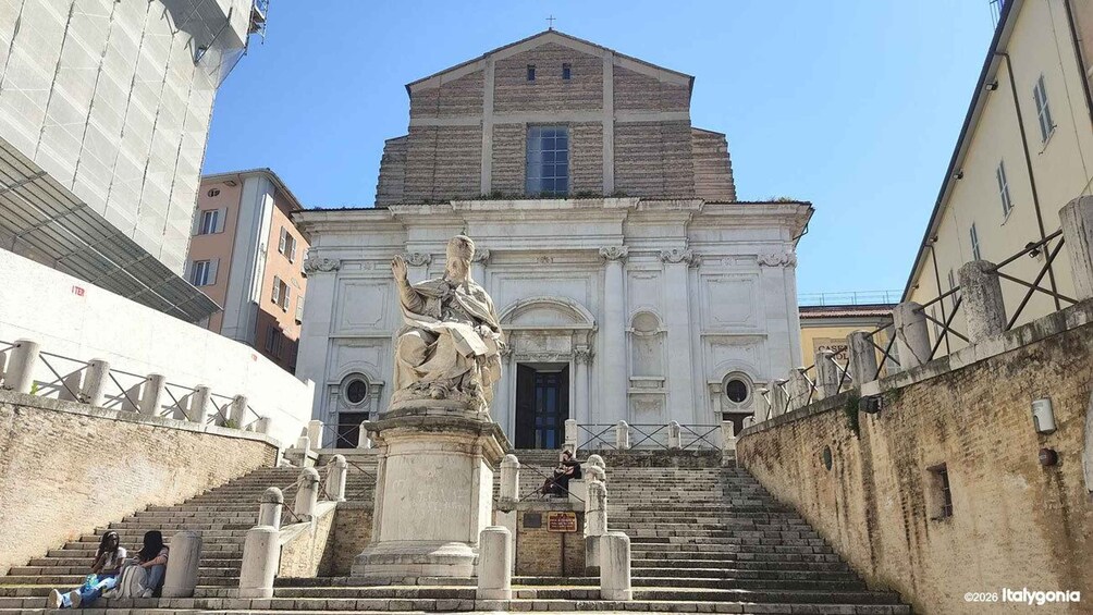 A historic church with a statue at the entrance, surrounded by old buildings. 5
