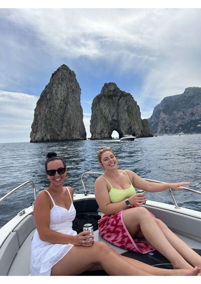 Two people on a boat with a rocky coastline in the background. 1