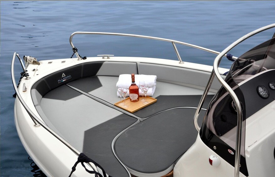 A boat with a grey cushioned seating area, a bottle of Prosecco, and two glasses on a tray. 1