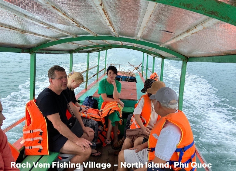 A group of people on a boat with life jackets, indicating a fishing activity in a village setting. 1