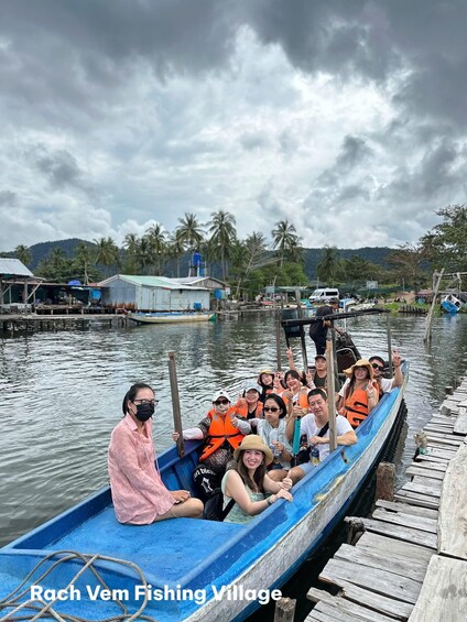 A group of people on a boat in a fishing village with palm trees and houses in the background. 4