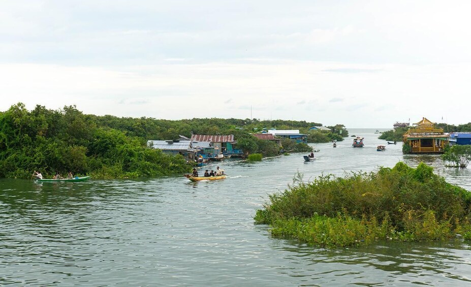 A river with boats, greenery, and buildings along the banks. 1
