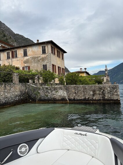 A boat named 'SeaRover' on calm water, a stone wall, and a historic building with red shutters. 2