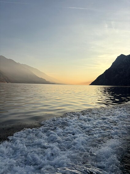 A calm lake with mountains in the background and a foamy shoreline. 5