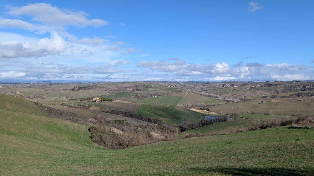 Rolling hills, a small body of water, and scattered buildings in a rural landscape. 5