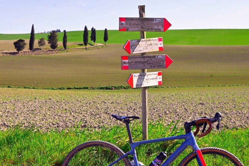 A bicycle parked in a field with directional signs. 3