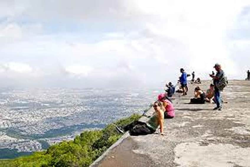 A group of people on a concrete ledge overlooking a cityscape. 3