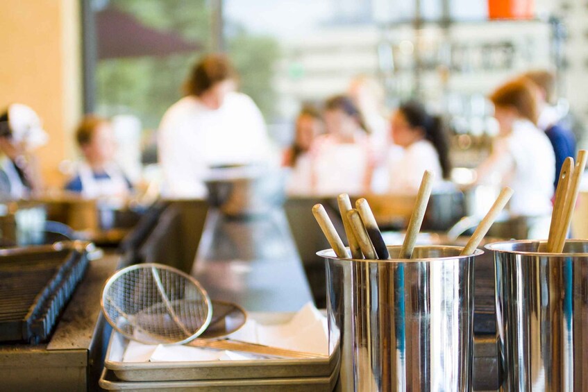 A restaurant interior with stainless steel condiment containers and a metal strainer on a counter. 5