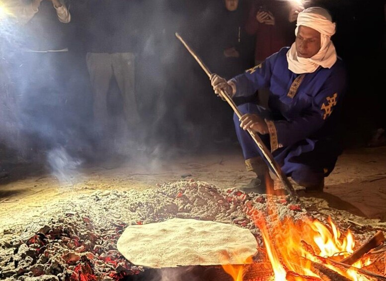 A person cooking over an open fire with a flatbread. 1