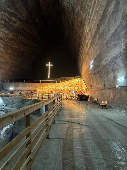 An illuminated cave interior with a wooden walkway and benches. 4