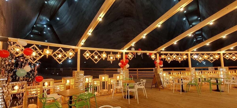 An indoor dining area with wooden tables and chairs, decorated with red and white balloons and string lights. 3