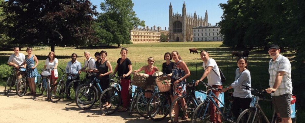A group of people on bicycles in a park with a historic building in the background. 1