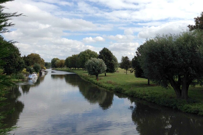A calm river with boats, surrounded by trees and a grassy area. 2