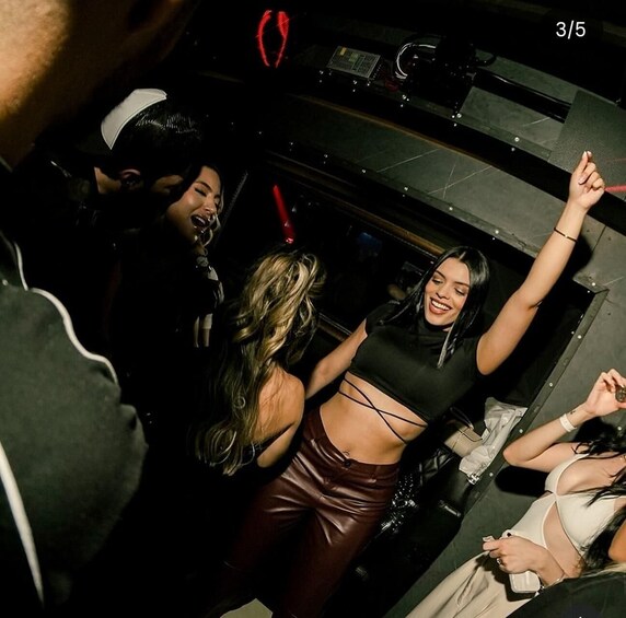 A group of people dancing in a dimly lit room with a DJ booth. 1