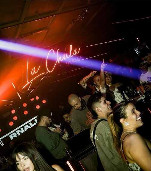A nightclub interior with neon signs and a crowd of people. 2