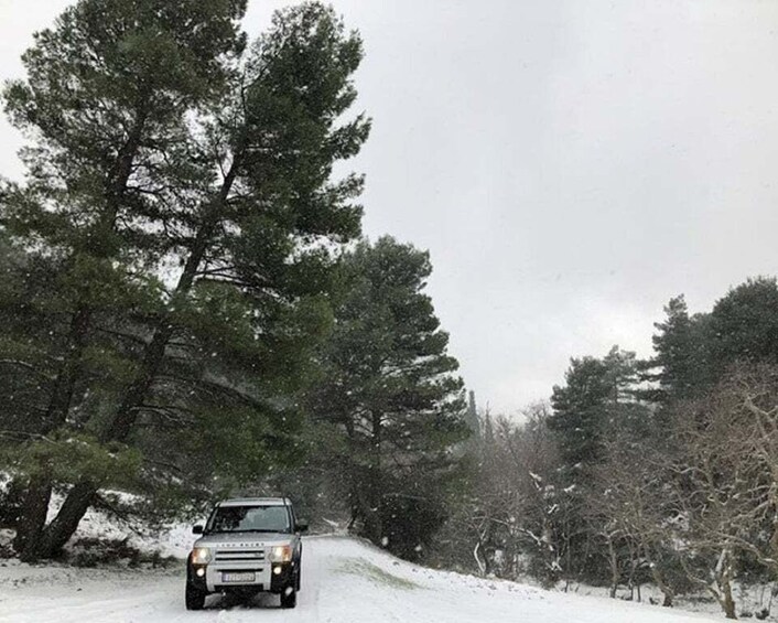 A vehicle driving on a snow-covered road with trees on both sides. 4