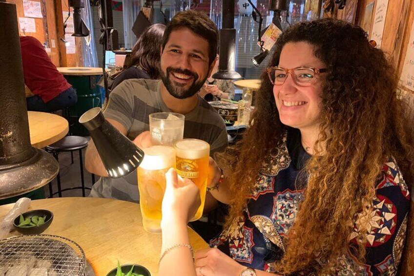 Two people toasting with large beer mugs at a bar. 2
