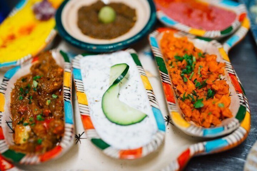 A variety of dishes on colorful paper plates, including a cucumber slice and a carrot dish. 2