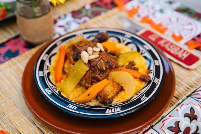 A traditional Moroccan tagine dish with meat, vegetables, and almonds on a patterned plate. 5