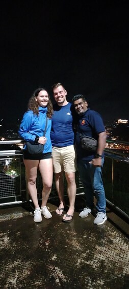 Tres personas de pie sobre un puente de noche. 4