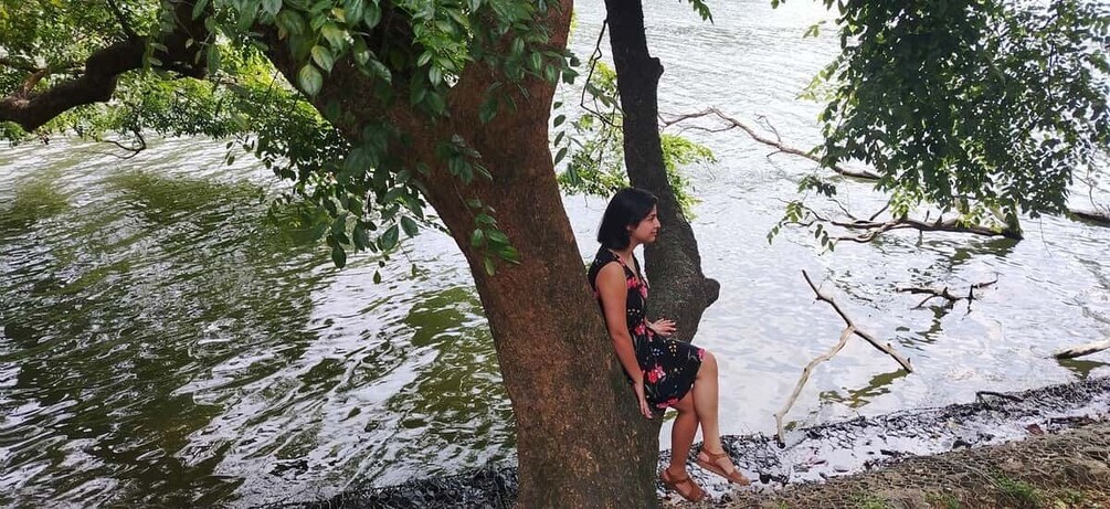 Una persona sentada en una rama de árbol junto al agua. 5