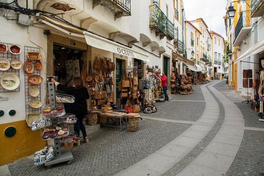 A narrow street with shops on either side, displaying various goods. 5