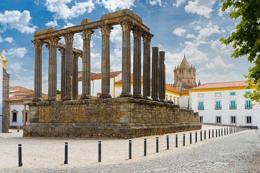 Ancient Roman columns, a cobblestone street, and a historic building with a tower. 3