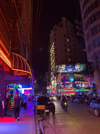 A busy street at night with neon signs, a 'No Parking' sign, and a building with illuminated windows. 4