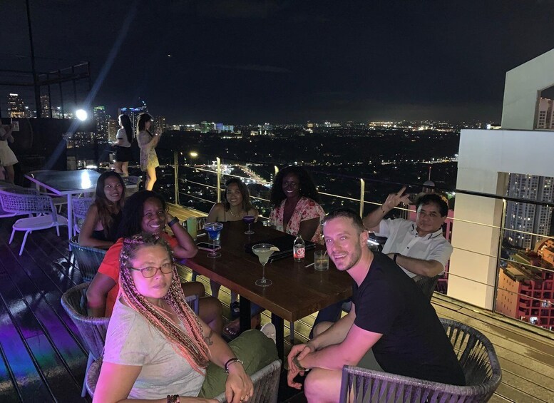 A group of people seated at a table with a cityscape view in the background. 3