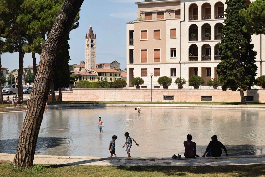 A public square with a water feature, surrounded by trees and buildings with arched windows. 4