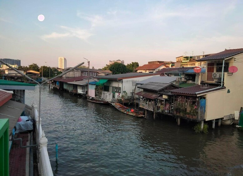 A river with floating houses, a boat, and a bridge. 2